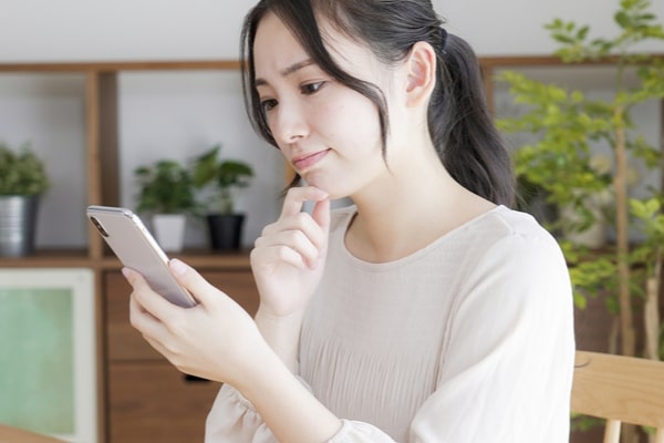 スマホを見て悩む女性